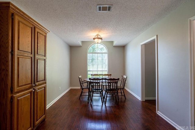 dining area with a textured ceiling and dark hardwood / wood-style flooring