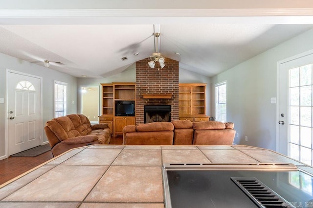 living room with brick wall, lofted ceiling, plenty of natural light, and hardwood / wood-style flooring