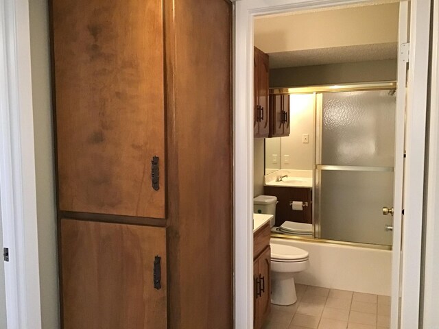 full bathroom with tile flooring, combined bath / shower with glass door, vanity, and toilet