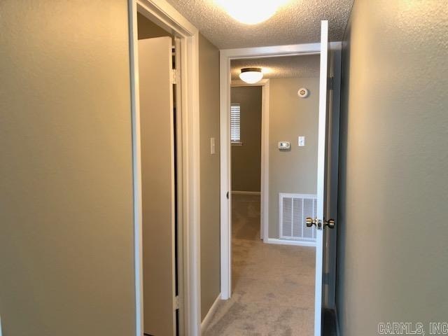 corridor with carpet floors and a textured ceiling