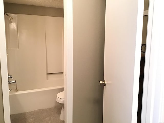 bathroom with a textured ceiling,  shower combination, and toilet