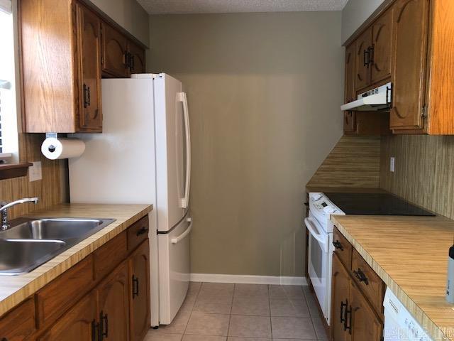 kitchen featuring backsplash, white appliances, sink, and tile flooring