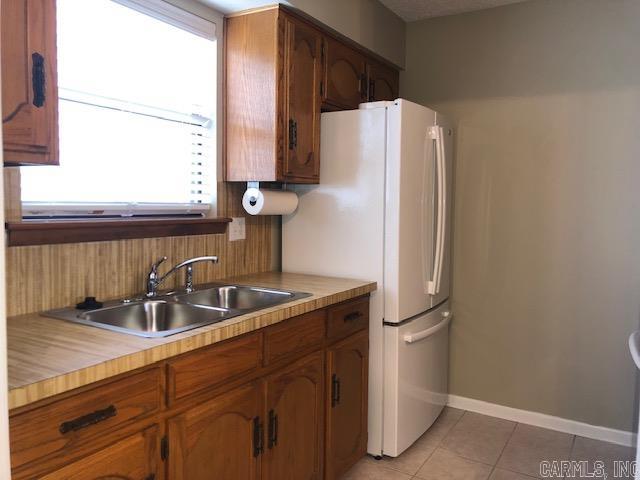 kitchen featuring white fridge, sink, and light tile flooring