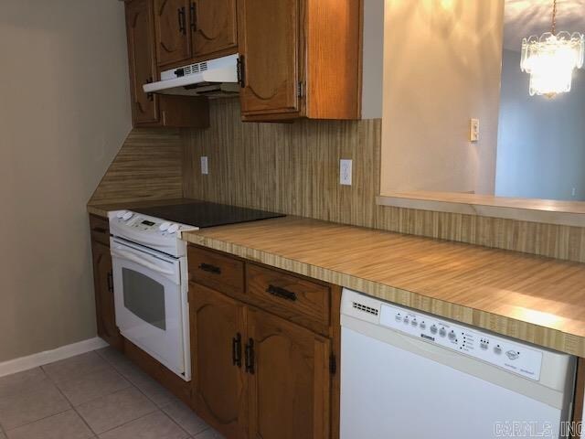 kitchen with light tile flooring, white appliances, a chandelier, and pendant lighting