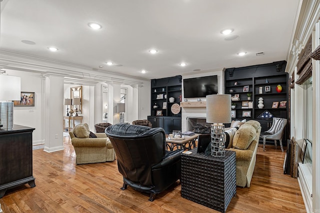 living room featuring light hardwood / wood-style flooring, decorative columns, built in shelves, and ornamental molding