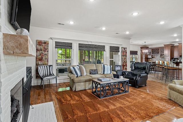 living room with ornamental molding, a chandelier, a fireplace, and dark hardwood / wood-style floors