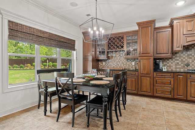 dining area with an inviting chandelier, crown molding, and light tile flooring