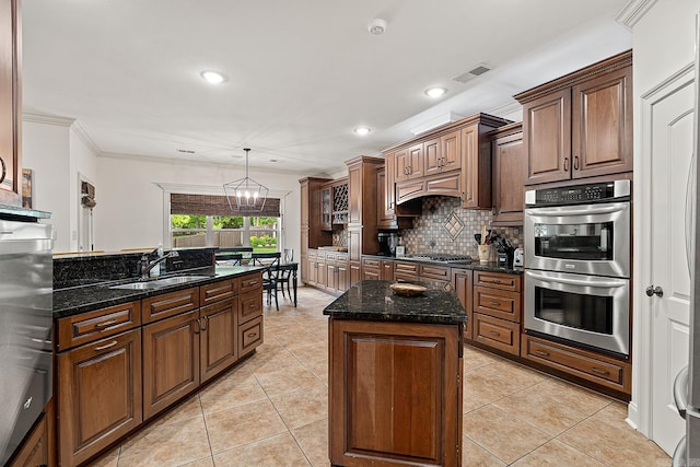 kitchen featuring decorative light fixtures, appliances with stainless steel finishes, tasteful backsplash, sink, and a center island