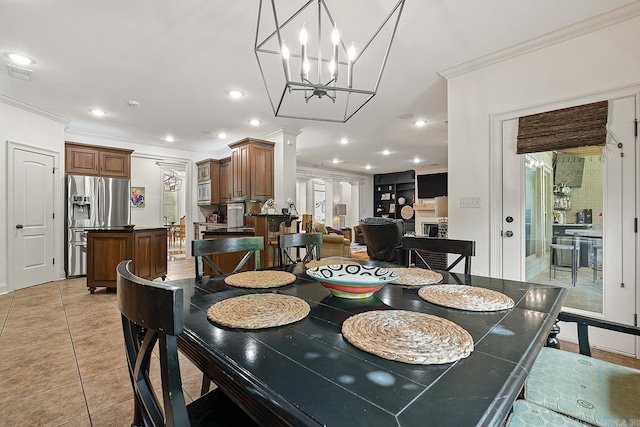 tiled dining space featuring ornamental molding, ornate columns, and an inviting chandelier