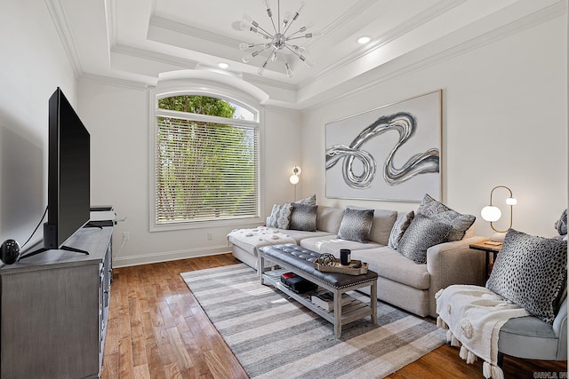 living room featuring ornamental molding, a chandelier, a tray ceiling, and dark hardwood / wood-style floors