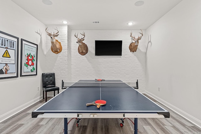 playroom with wood-type flooring and brick wall