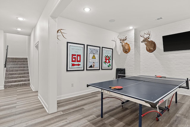 recreation room featuring light hardwood / wood-style flooring and brick wall