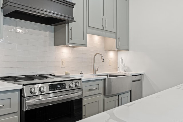 kitchen featuring tasteful backsplash, gray cabinets, stainless steel appliances, and light stone counters