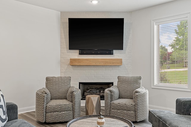 sitting room featuring a wealth of natural light, dark wood-type flooring, and brick wall