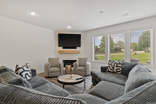 living room featuring brick wall, dark hardwood / wood-style flooring, and a brick fireplace