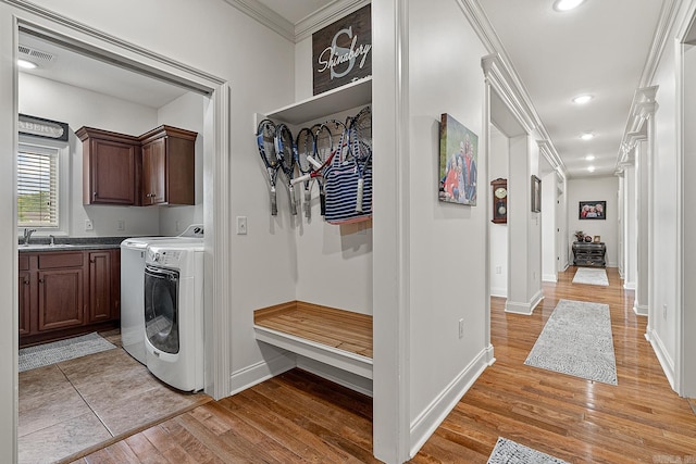 laundry room with washing machine and dryer, cabinets, crown molding, sink, and light tile floors