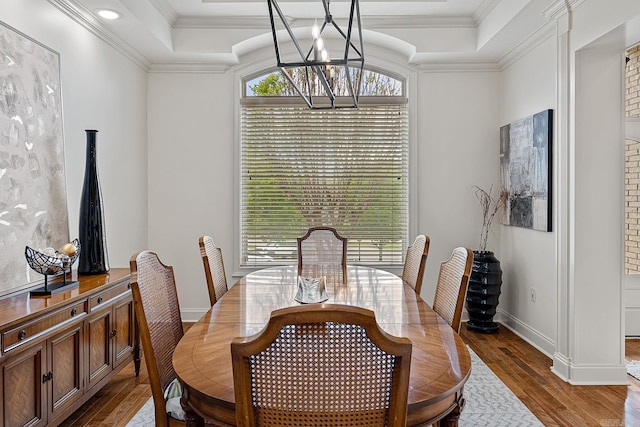 dining area with dark hardwood / wood-style flooring, a raised ceiling, and an inviting chandelier