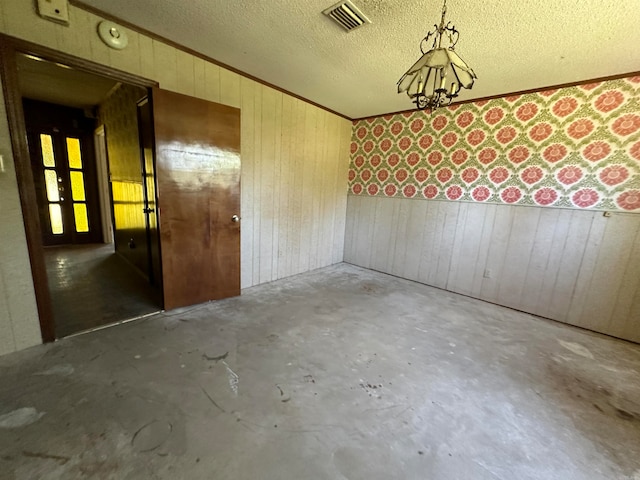 empty room with wood walls, concrete flooring, and a textured ceiling