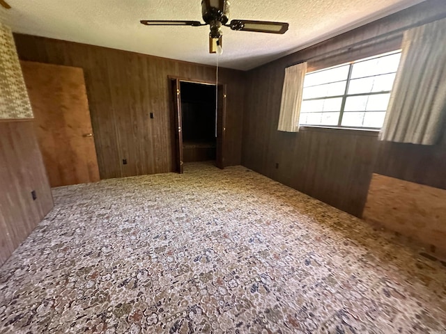 spare room with a textured ceiling, ceiling fan, and carpet flooring