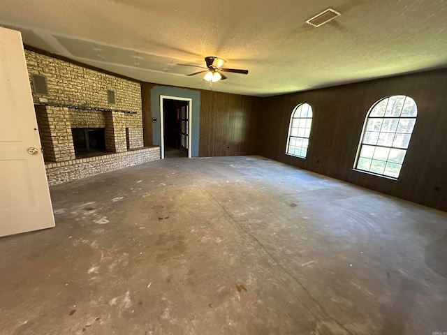 unfurnished living room with concrete flooring, a fireplace, and wood walls