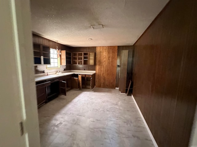 kitchen with a textured ceiling, sink, and wooden walls