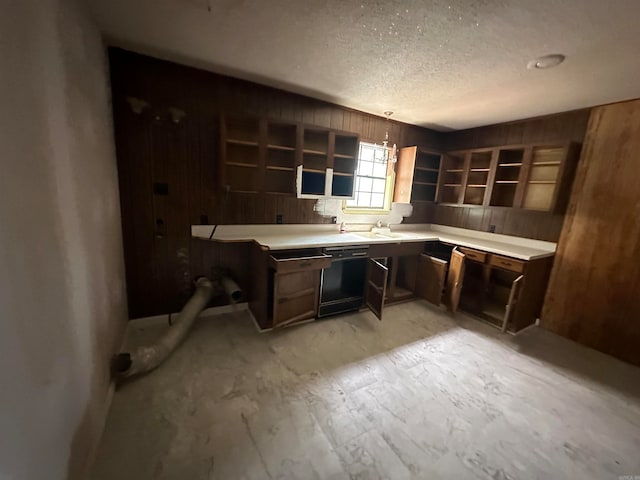 kitchen featuring black dishwasher, wood walls, dark brown cabinetry, and a textured ceiling