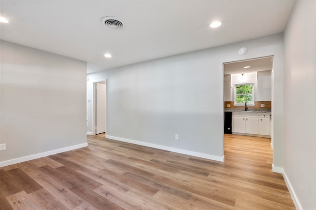 unfurnished room with sink and light hardwood / wood-style floors