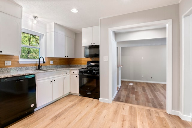 kitchen featuring white cabinets, black appliances, sink, and light wood-type flooring