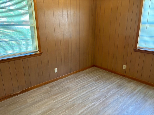 unfurnished room featuring light hardwood / wood-style flooring and wooden walls