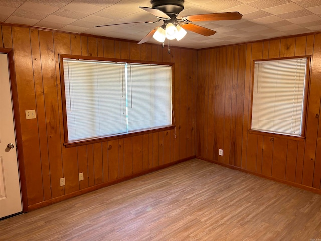 empty room with light hardwood / wood-style floors and wooden walls