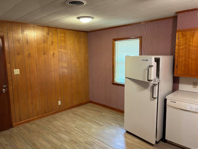 kitchen featuring light hardwood / wood-style floors, wooden walls, and white appliances