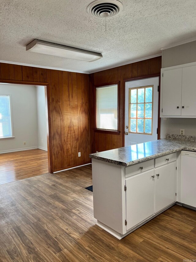 kitchen featuring white cabinets, wood walls, hardwood / wood-style floors, and a textured ceiling