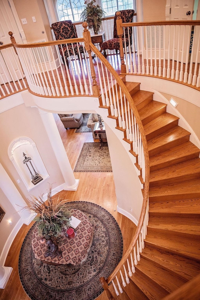 stairs with hardwood / wood-style floors and a high ceiling