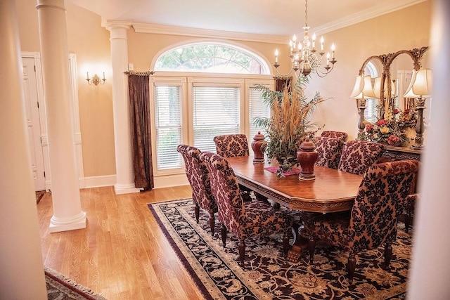 dining area featuring a chandelier, light hardwood / wood-style floors, decorative columns, and crown molding