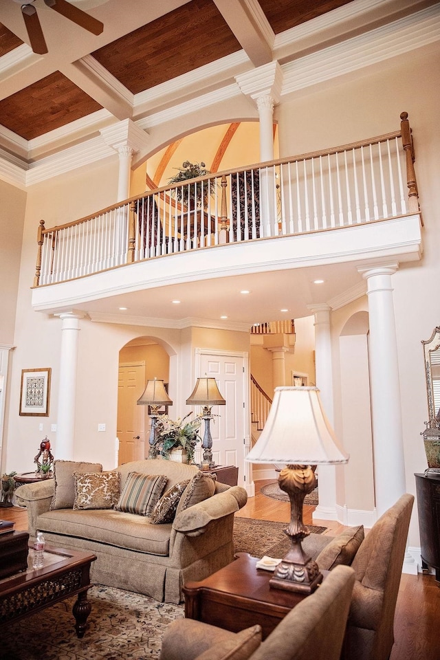 living room featuring coffered ceiling, hardwood / wood-style floors, crown molding, and ornate columns