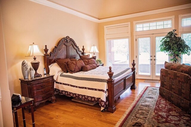 bedroom featuring vaulted ceiling, access to exterior, hardwood / wood-style flooring, ornamental molding, and french doors