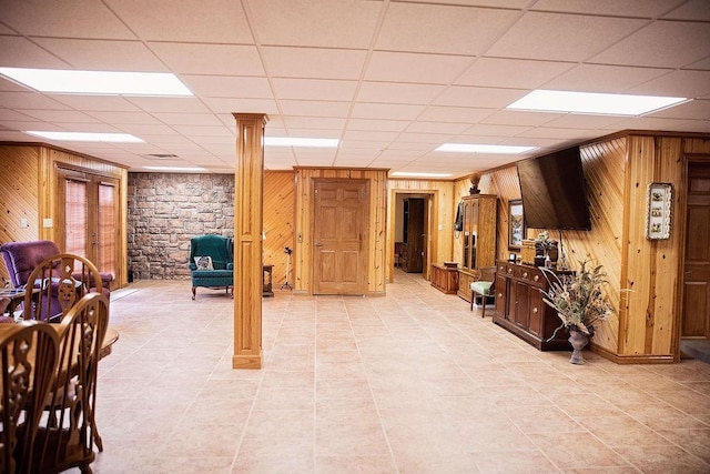 interior space with wooden walls, light tile floors, and a drop ceiling