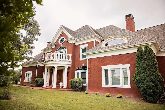 view of front of home with a front yard and a balcony