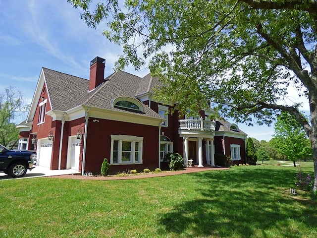 view of front of property featuring a garage, a balcony, and a front lawn