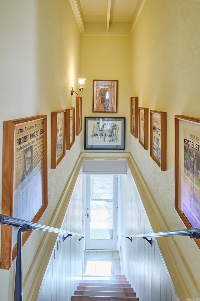 stairs with beam ceiling, crown molding, and tile floors