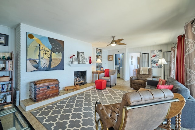 living room featuring a fireplace, ceiling fan, and brick wall