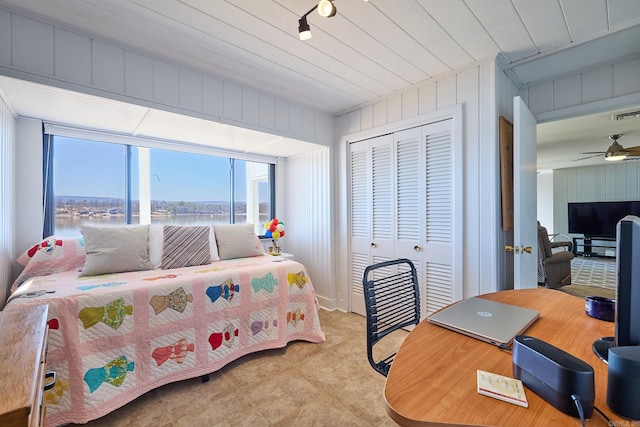 bedroom with a closet, a water view, ceiling fan, and track lighting