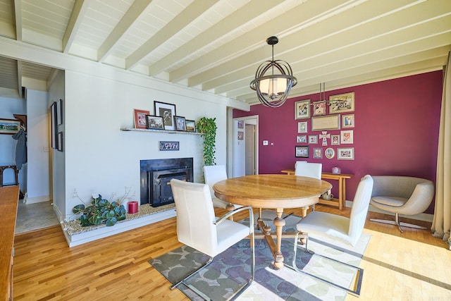 dining space with beam ceiling, hardwood / wood-style flooring, and an inviting chandelier