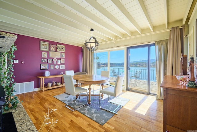 dining room featuring hardwood / wood-style flooring, beamed ceiling, a notable chandelier, and a water and mountain view