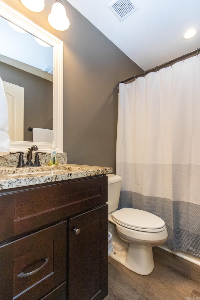 bathroom featuring toilet, hardwood / wood-style floors, walk in shower, and vanity