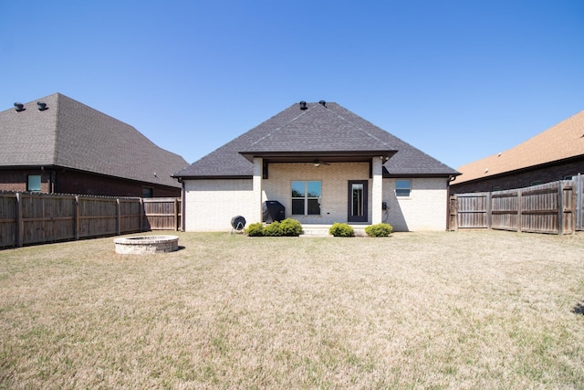 rear view of house featuring a fire pit and a lawn