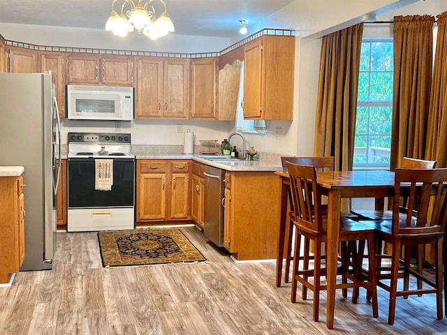 kitchen featuring sink, decorative light fixtures, stainless steel appliances, light hardwood / wood-style flooring, and an inviting chandelier