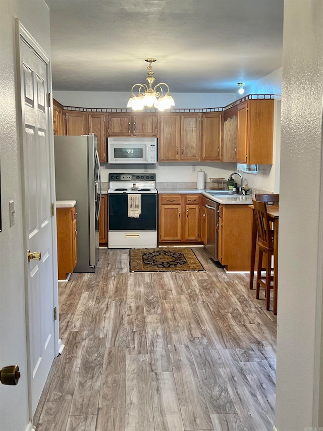 kitchen with a notable chandelier, light hardwood / wood-style floors, sink, decorative light fixtures, and stainless steel appliances