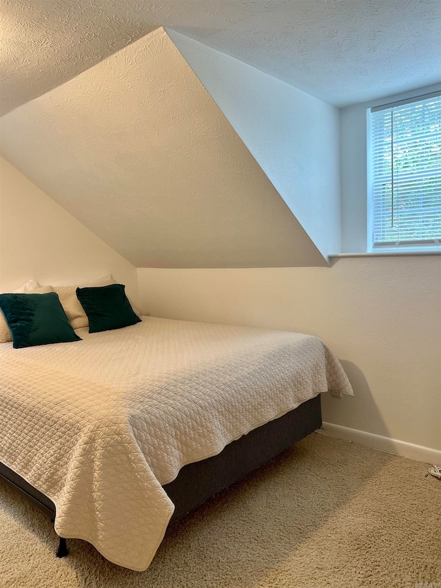 carpeted bedroom featuring a textured ceiling and lofted ceiling