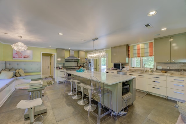 kitchen featuring backsplash, wall chimney range hood, a center island, and light stone counters